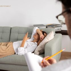 femeie care sta întinsă pe o canapea, discutând cu un terapeut